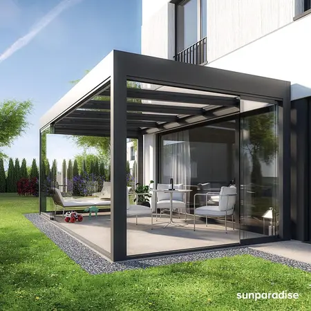 Moderner Wintergarten aus Glas und Aluminium an einem Einfamilienhaus mit Gartenmöbeln.