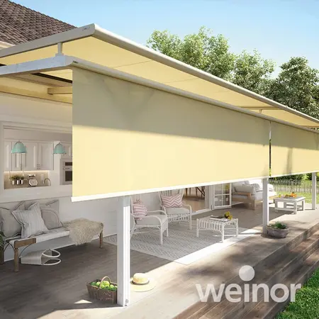 Große gelbe Terrassenmarkise spendet Schatten auf einer modernen, gemütlichen Veranda.