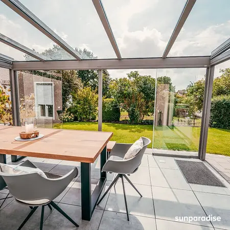 Moderner Wintergarten mit Glasdach, Gartenblick und stilvoller Terrasseneinrichtung.